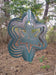 Trillium Wind Spinner in Blue Copper with woodland background